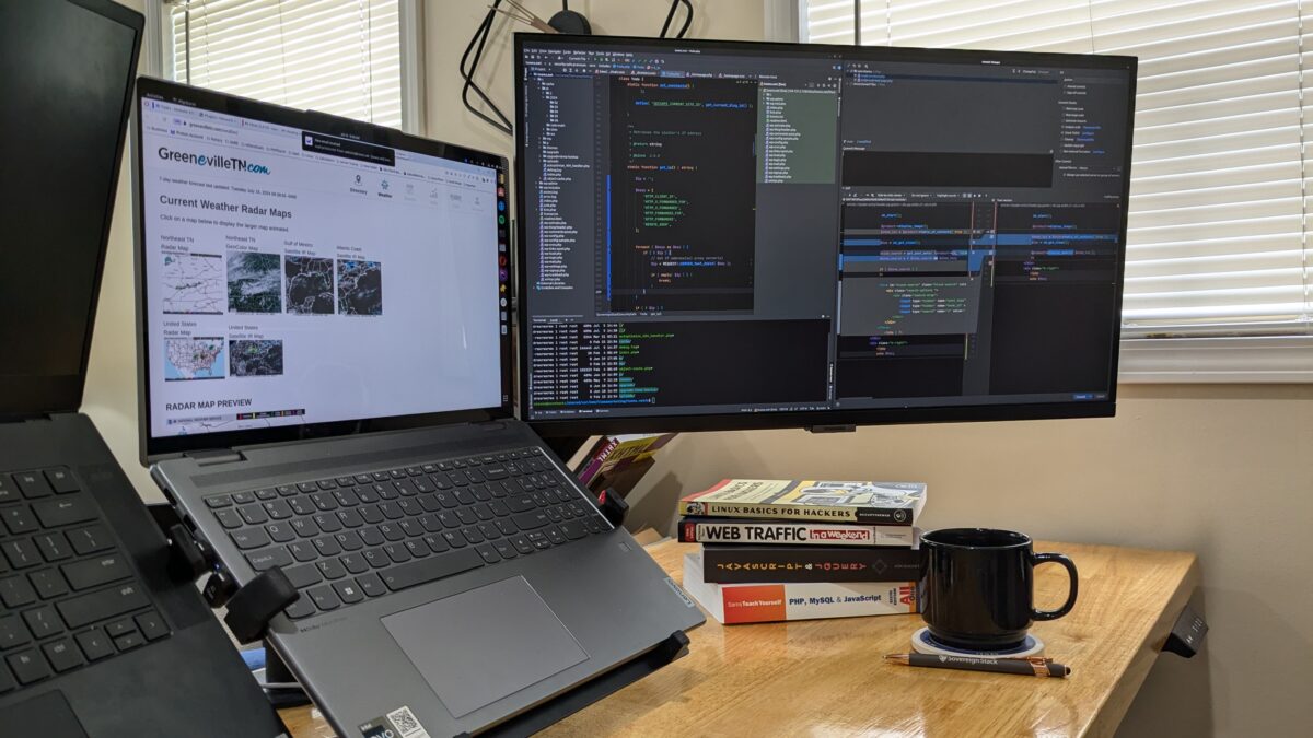 Laptop showing website on the screen and a larger screen showing web programming code